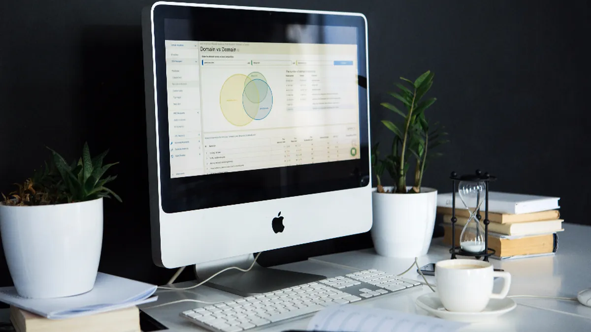 A desk with a computer, plant and planner ready for a new job