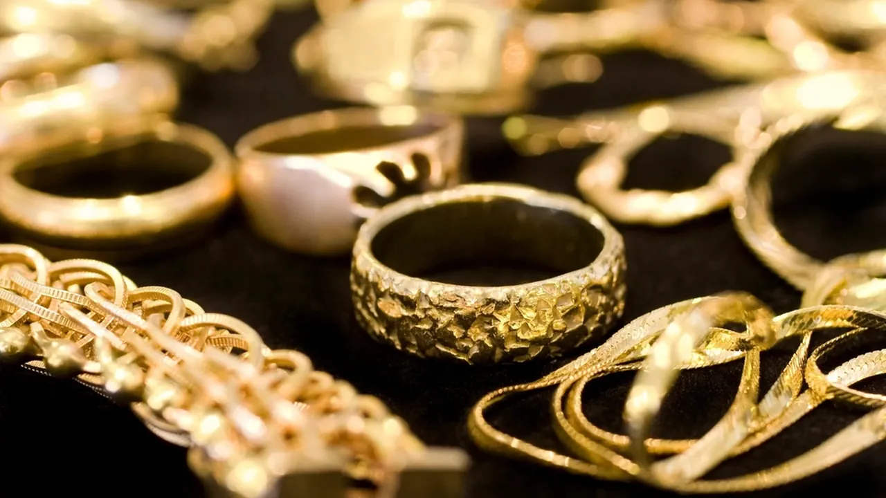 A close-up of gold rings and jewellery on a dark display