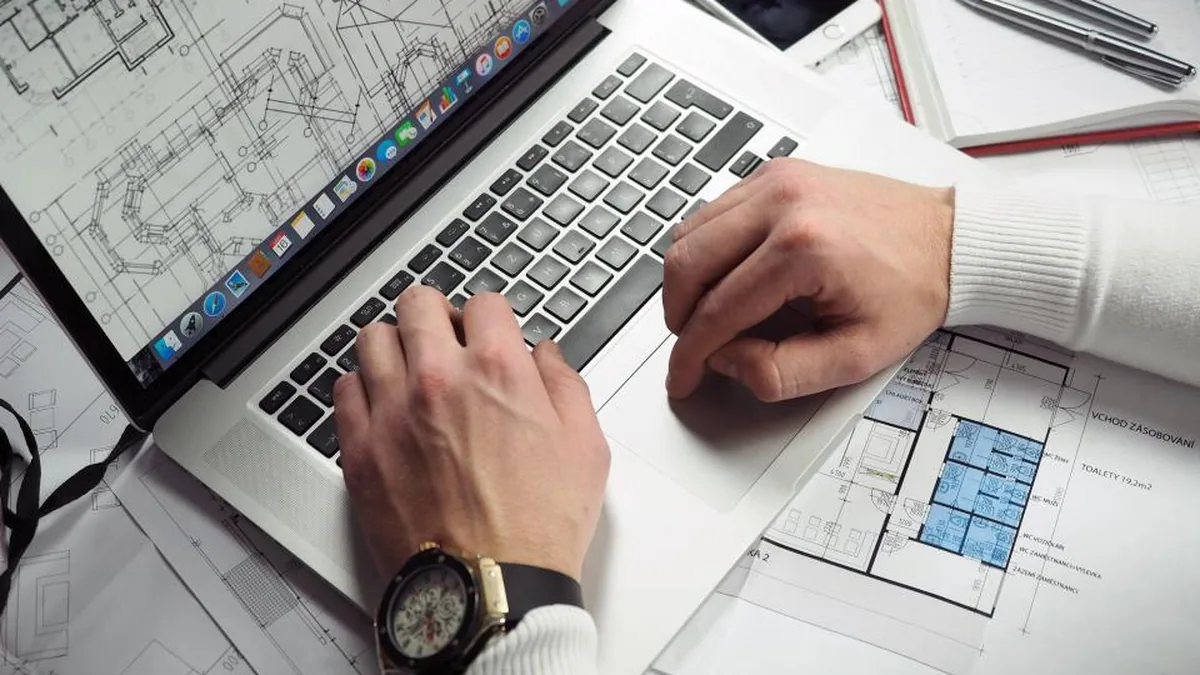 Working at a desk with a laptop and plans
