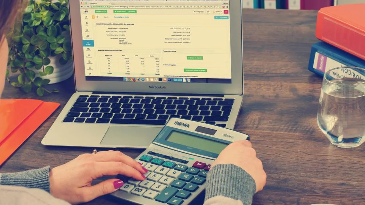 Person comparing financial figures on paper and screen