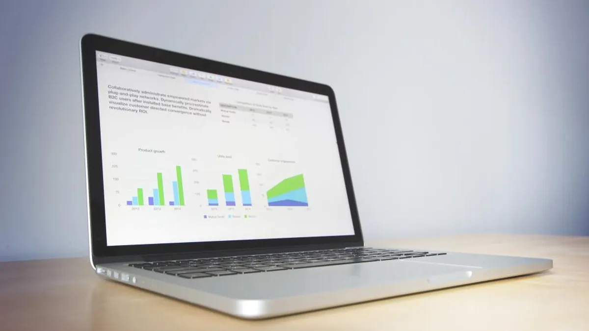 A laptop on a desk displaying charts and graphs