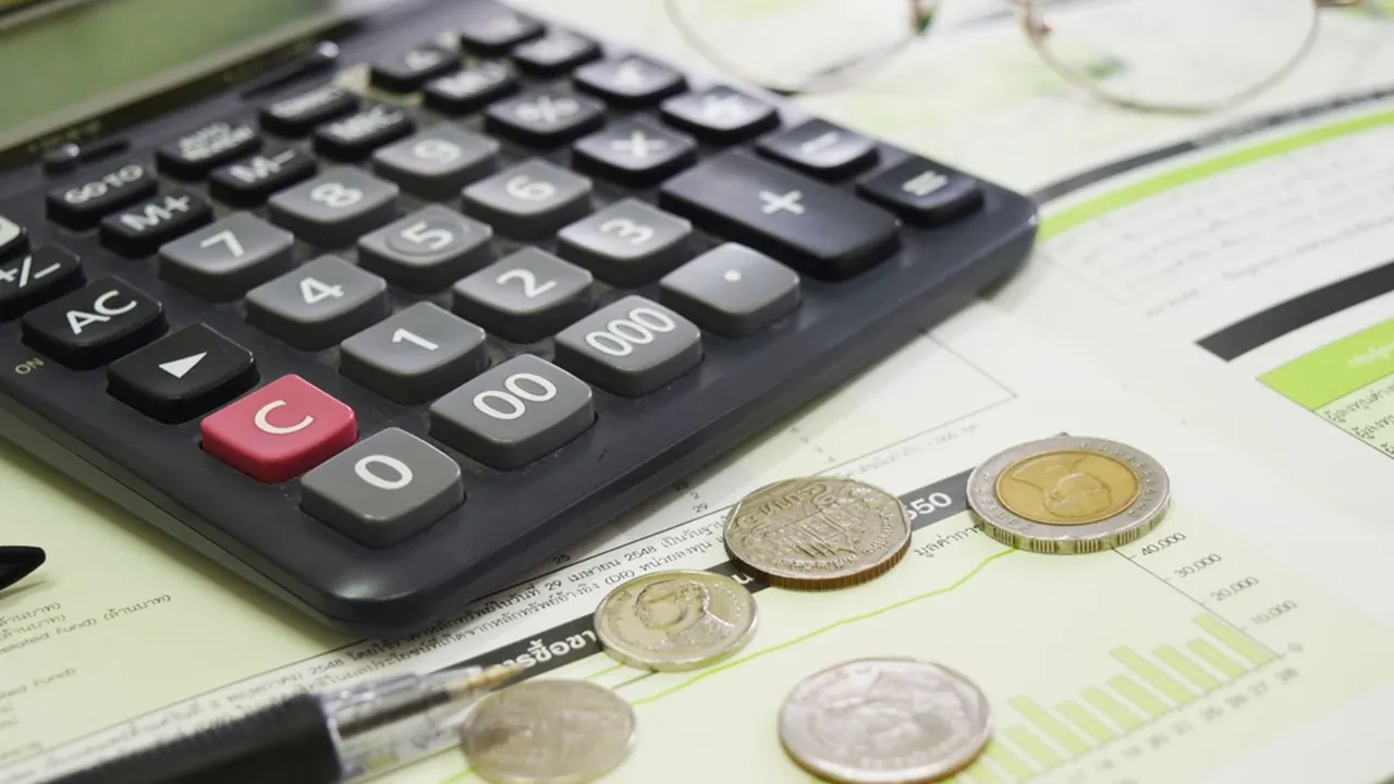 A calculator, coins and paperwork on a desk