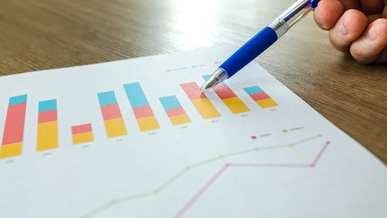 A pen pointing at a rising bar chart