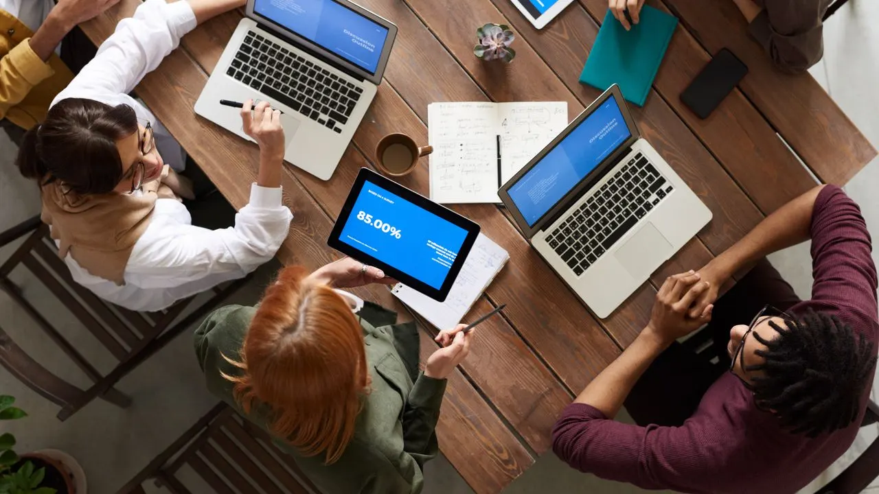 A training group working together around laptops at a large table