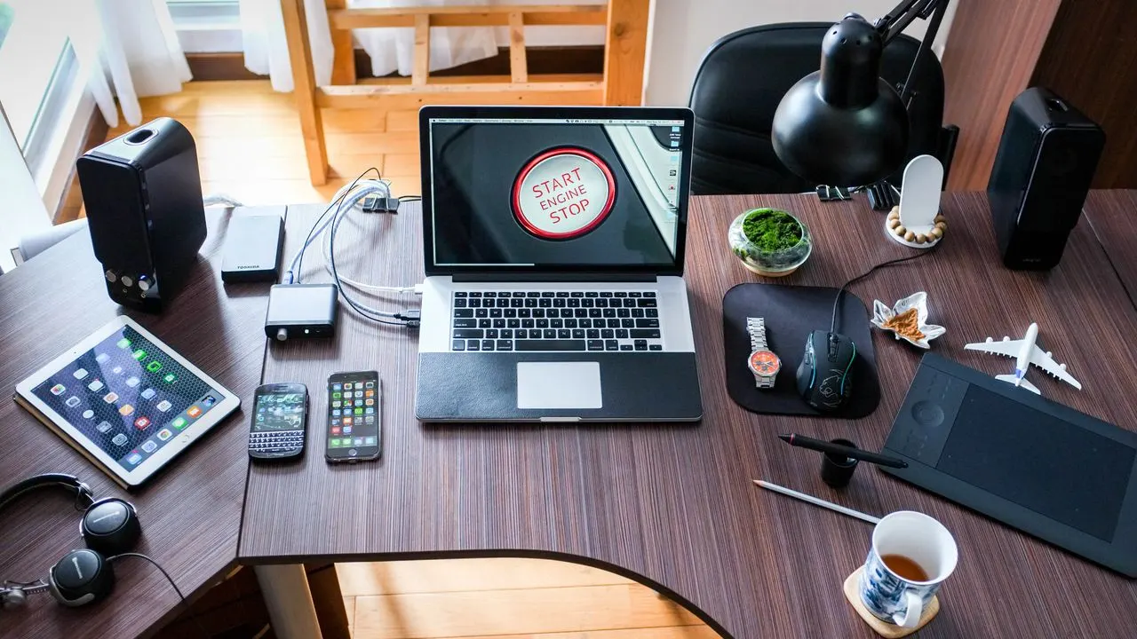 A home study desk with a laptop, tablet and phones