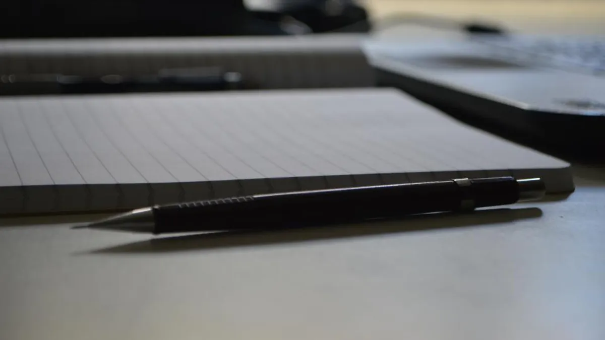 A blank notepad and pen on a desk