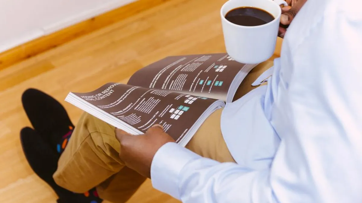 A person reading business reports with a cup of coffee