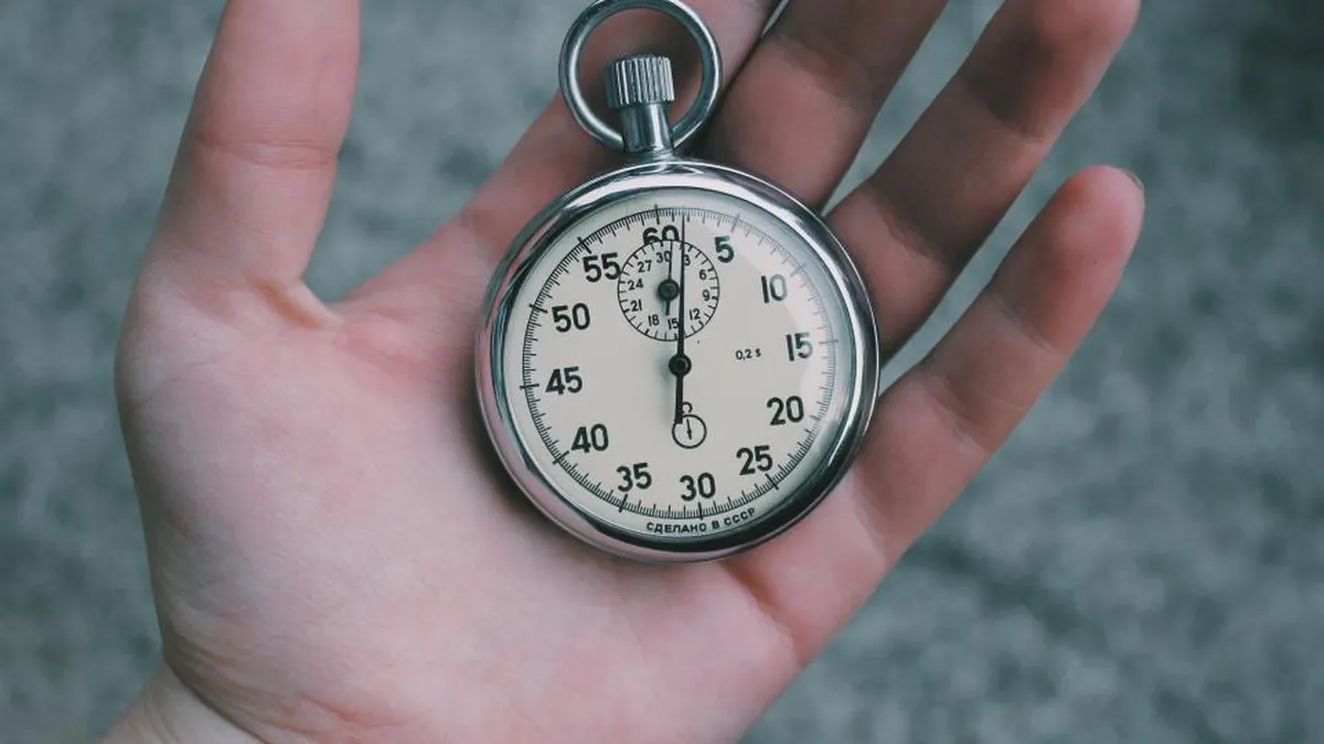 A hand holding a pocket stopwatch