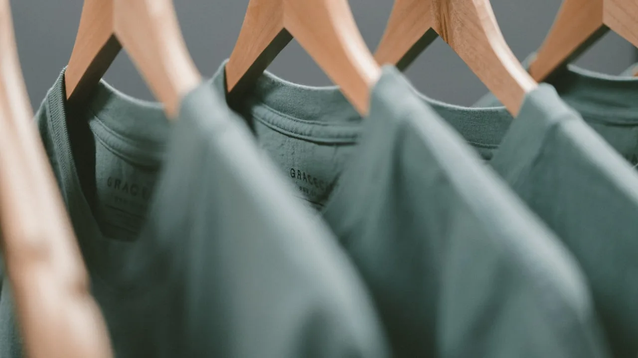 A rail of premium garments on wooden hangers in a boutique