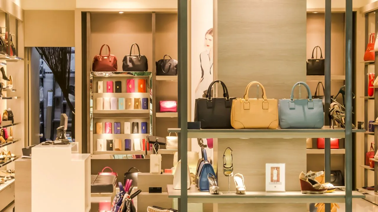 The interior of a luxury boutique with designer handbags and shoes displayed on lit shelves