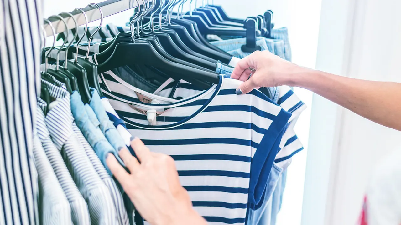 A shopper browsing striped shirts on a rail in a bright fashion boutique