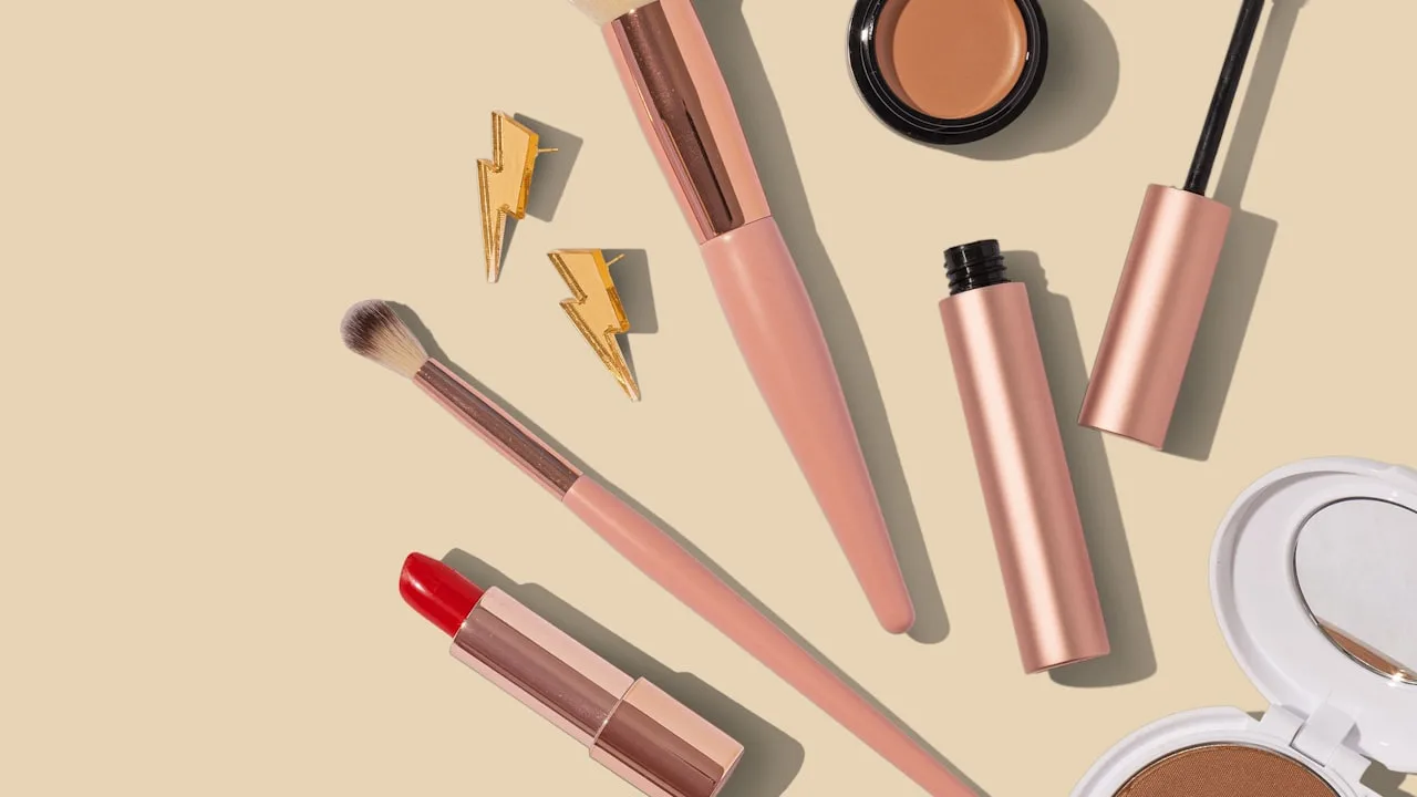 A flat-lay of premium cosmetics and gold jewellery on a neutral background