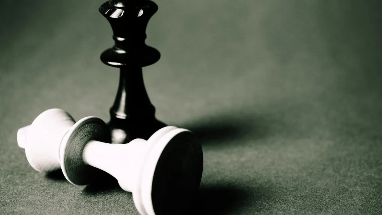 A fallen chess king lying beside a standing piece