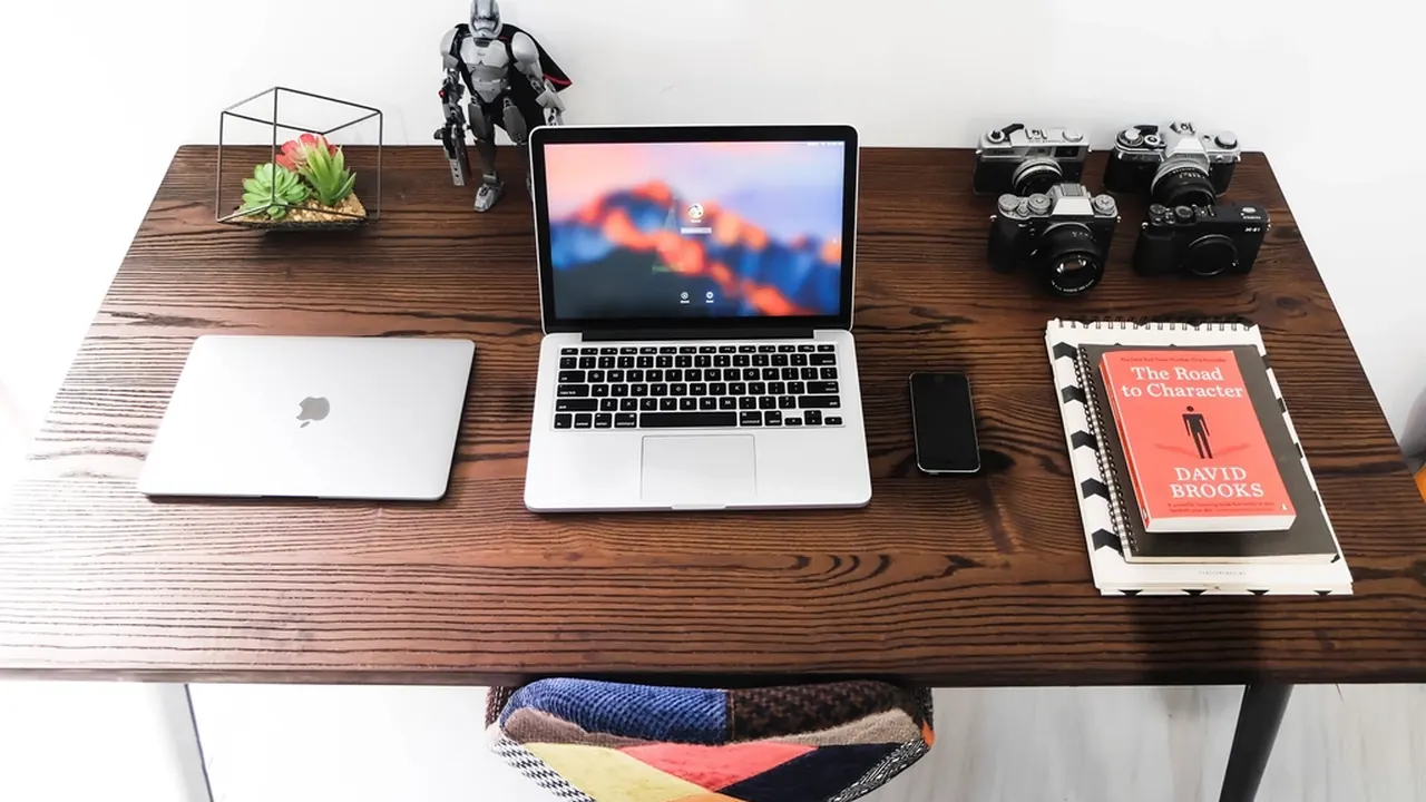A tidy designer's desk with a laptop, camera and tablet