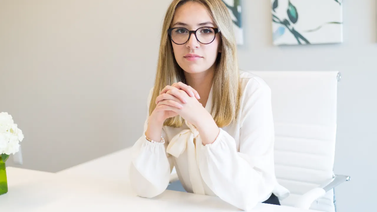 A professional woman seated at a white desk, ready for an interview