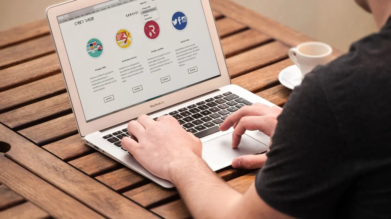 A person browsing a website on a laptop beside a coffee