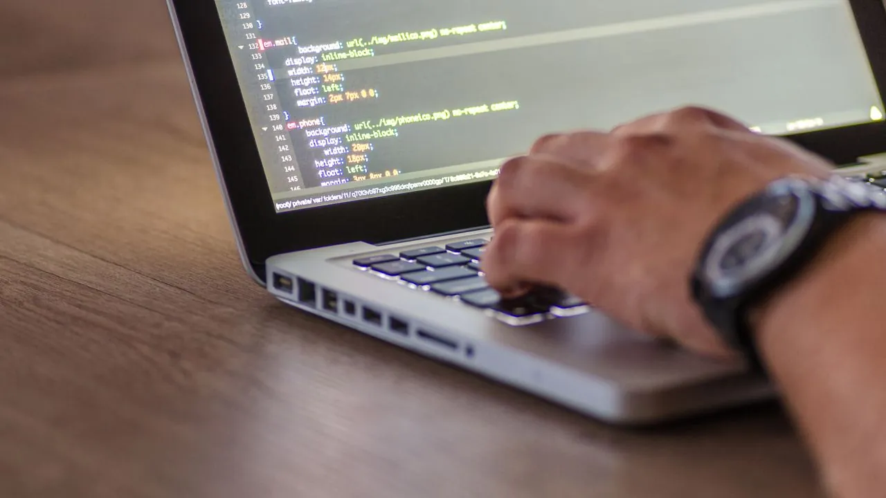 A laptop and notebook on a desk, set up for learning new digital skills