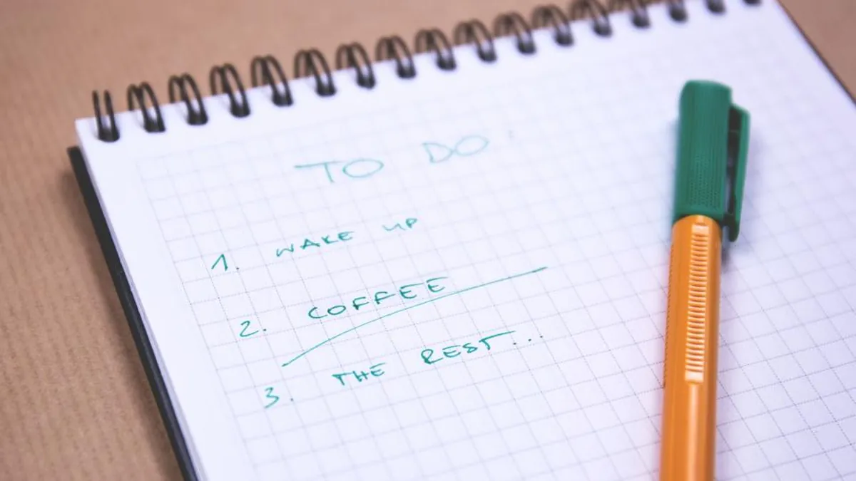 A handwritten to-do list on a notepad with a pen