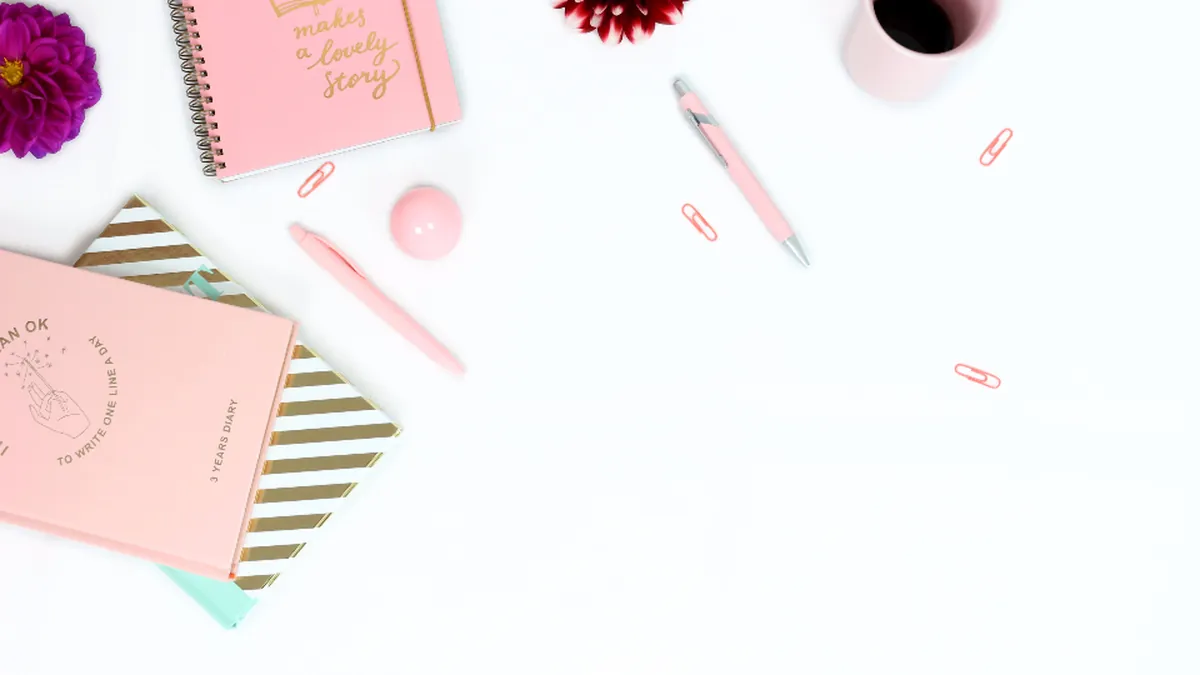 Notebooks, a pen and flowers arranged on a white desk